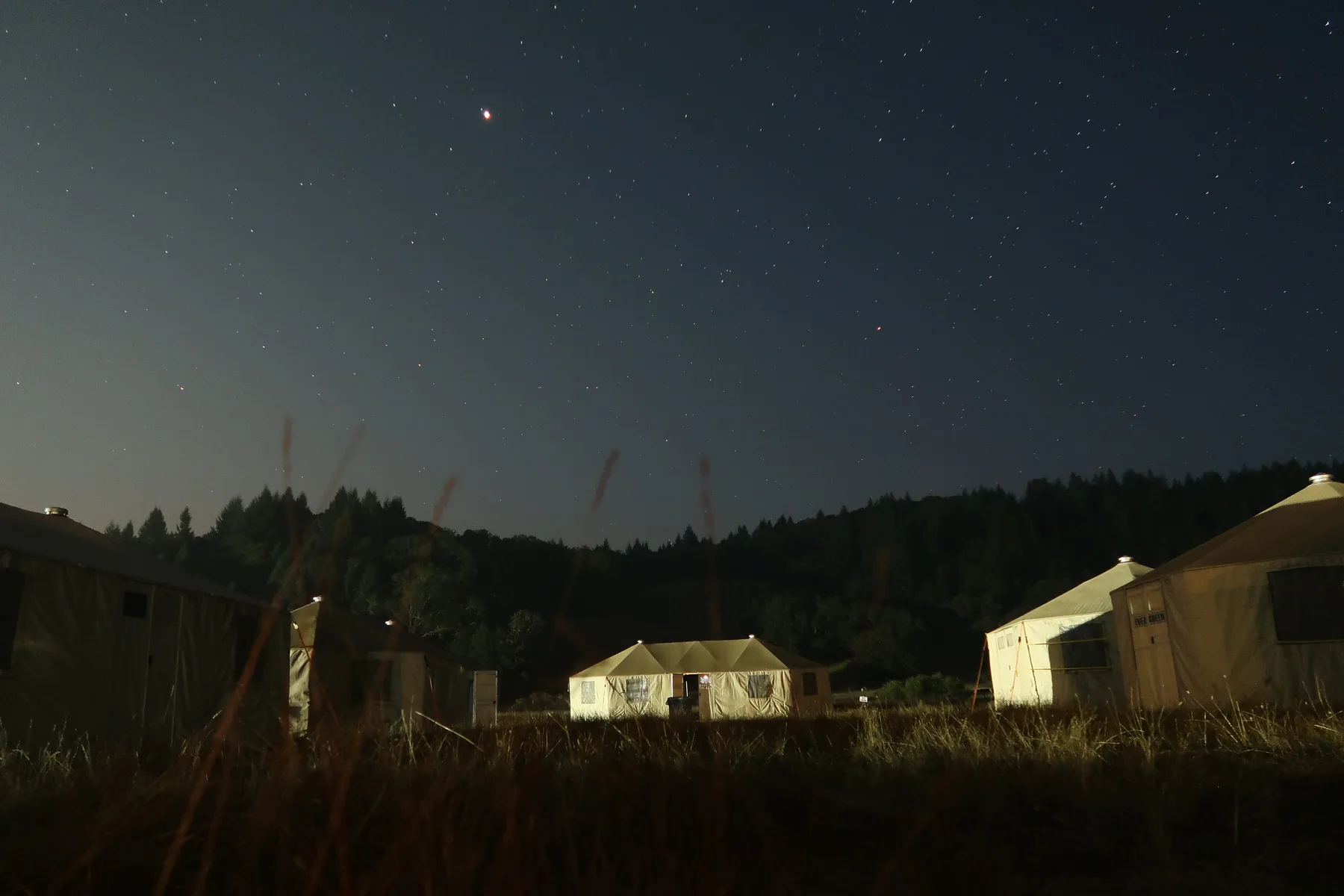 An Evergreen Resource base camp at night, yurts lit against a starry sky
