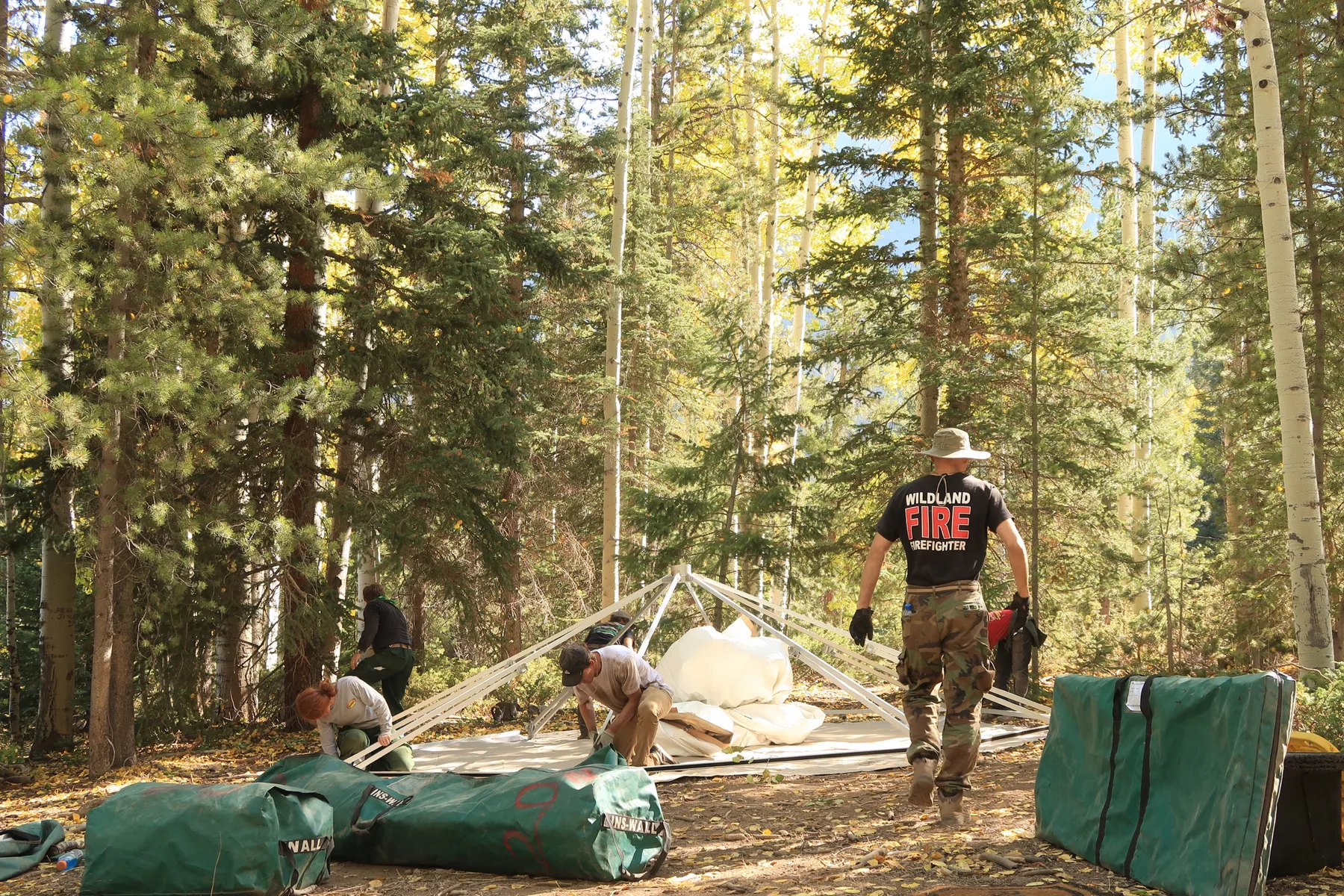 The Evergreen crew assembling a yurt frame on an incident with a wildland firefighter on site