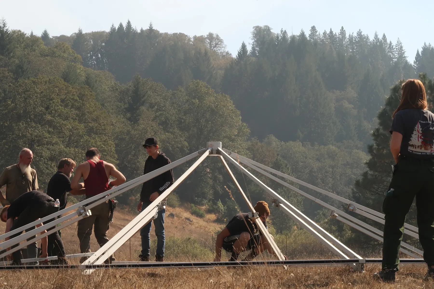 Closer angle on the Evergreen crew raising the metal frame of a yurt before the canvas goes on