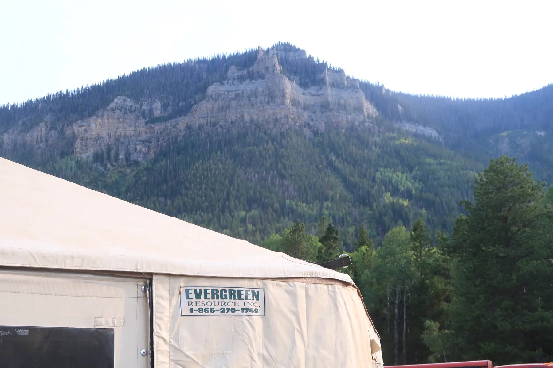 An Evergreen yurt with a craggy mountain peak rising behind the camp