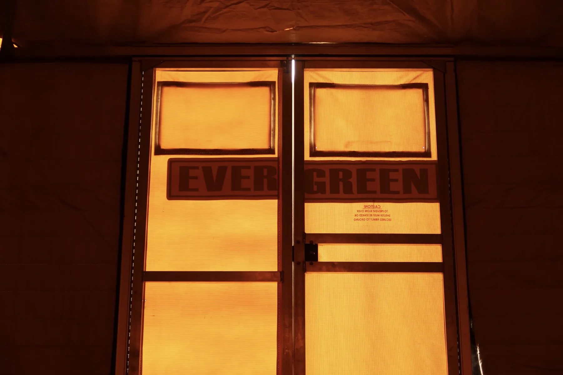 The interior double doors of an Evergreen yurt lit warm at golden hour