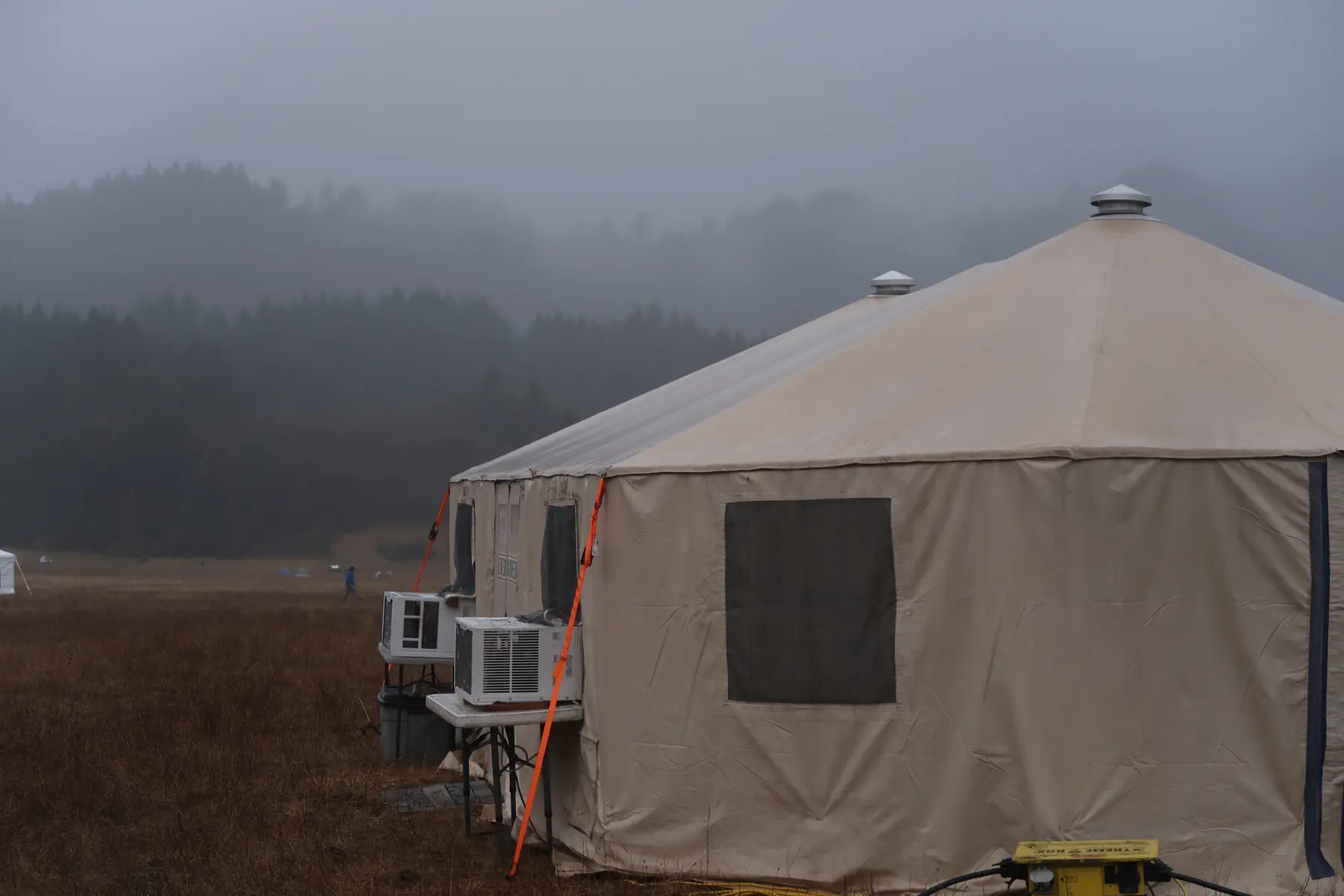 A single Evergreen yurt with an air-conditioning unit standing in heavy morning fog
